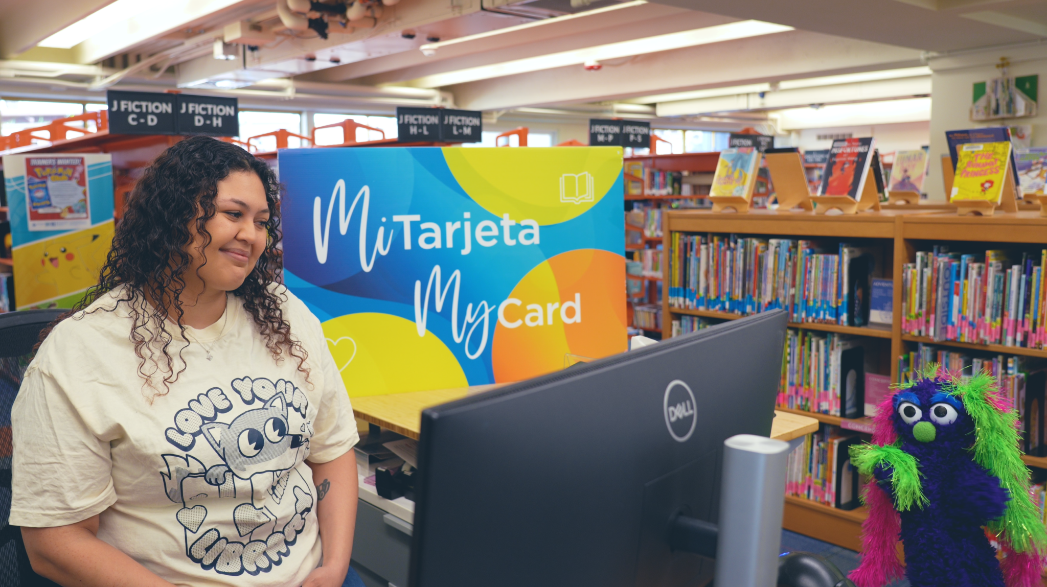 Librarian and Dewey in library in front of large Student MyCard